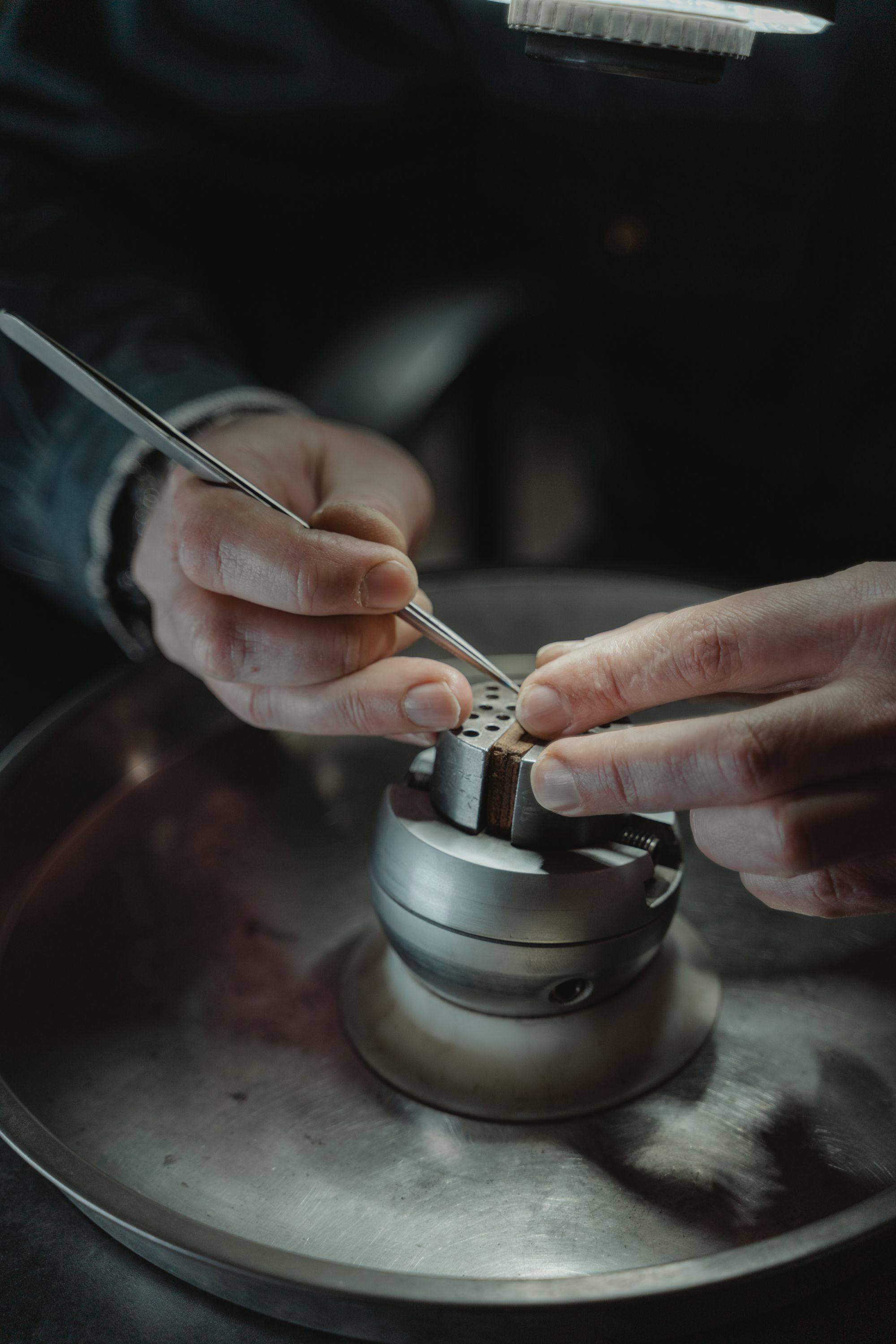 A jeweler setting a stone by hand at the bench